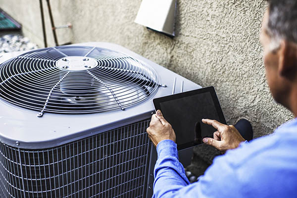 HVAC technician inspecting both a furnace and air conditioner